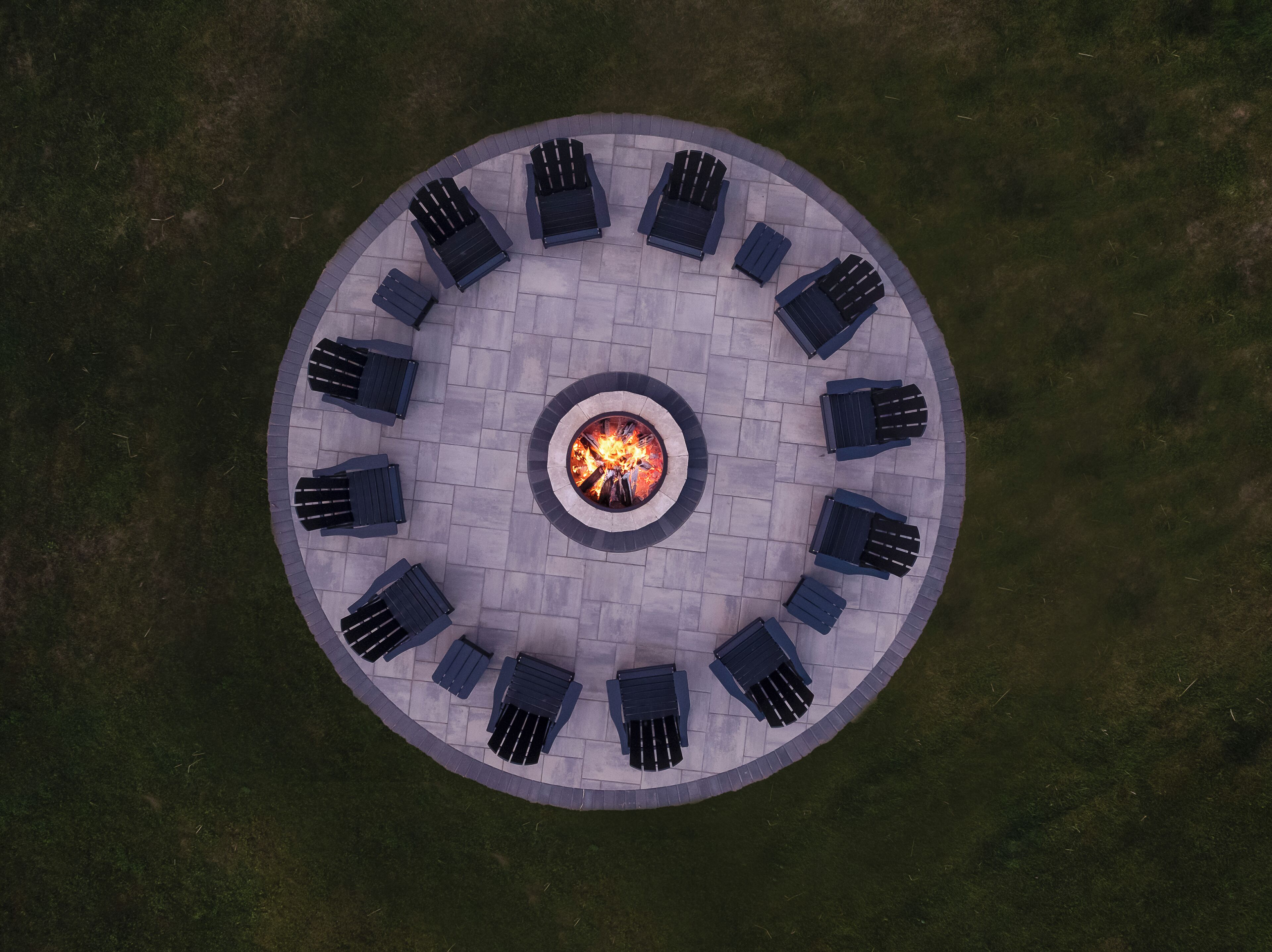 An aerial view of a circular outdoor seating area with a central fire pit surrounded by chairs.