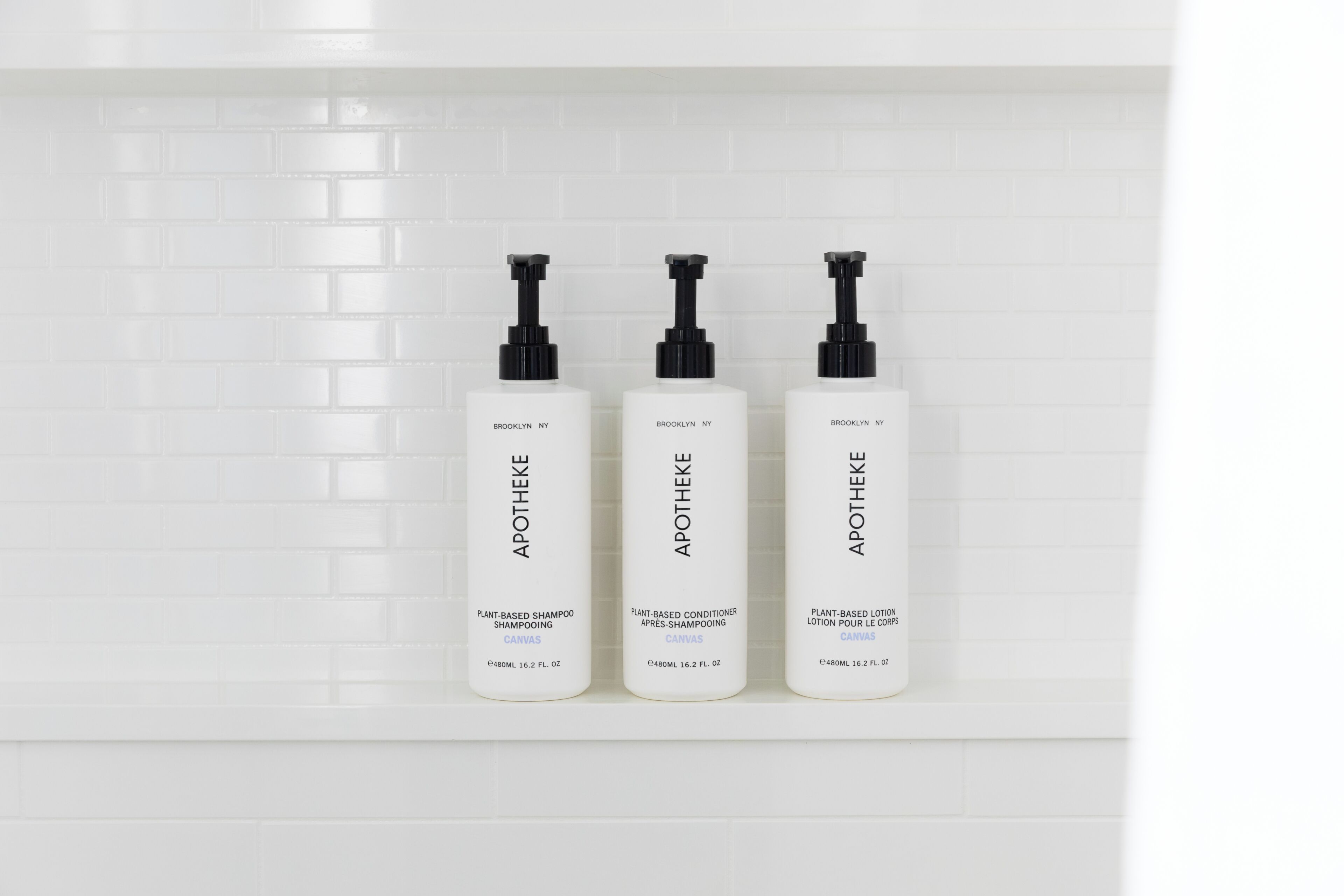 Three bottles of Brooklyn NY Apotheke plant-based products on a white tiled shelf.