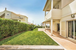 A residential property with a well-maintained lawn, a covered patio area, and a two-story building with balconies.