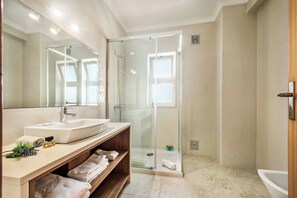 A modern bathroom with a glass shower enclosure, a sink, and a vanity with towels.