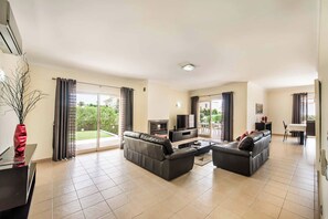 A spacious living room with a sofa set, a flat-screen TV, and a dining area.