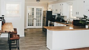 A modern kitchen with white cabinets, a wooden countertop, and a central island. - RANCH RETREAT, Beautiful 3-bedroom house in Columbus, MS (Columbus)
