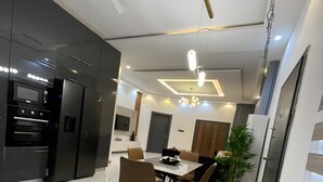Eine moderne Küche mit eingebauten Geräten, ein Essbereich mit Tisch und Stühlen und eine Decke mit Einbuchtungslampen.