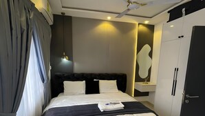 Ein modernes Hotelzimmer mit einem großen Bett, einem Deckenventilator und einem Kleiderschrank.