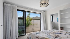 Et soveværelse med en stor seng, en skydedør til en balkon og et walk-in closet.