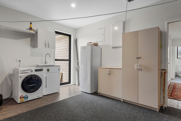 A modern kitchen with a washing machine, a refrigerator, and a cabinet.