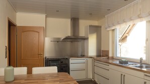 A compact kitchen with a wooden dining table, white cabinets, and a built-in oven. - Apartment MiA Cozy apartment near the Edersee and National Park (Frankenau)