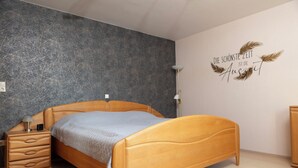 A bedroom with a wooden bed, a nightstand, a lamp, and a wall with a decorative sign. - Apartment MiA Cozy apartment near the Edersee and National Park (Frankenau)