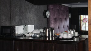 A kitchen with a microwave, toaster, kettle, and various kitchenware on the counter. - Falcon Guesthouse (Upington)