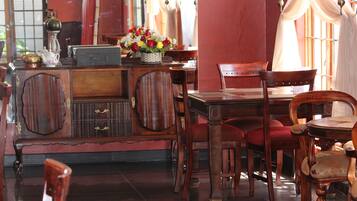 A traditional wooden dining table with chairs, a cabinet with drawers, and a vase with flowers on the table.