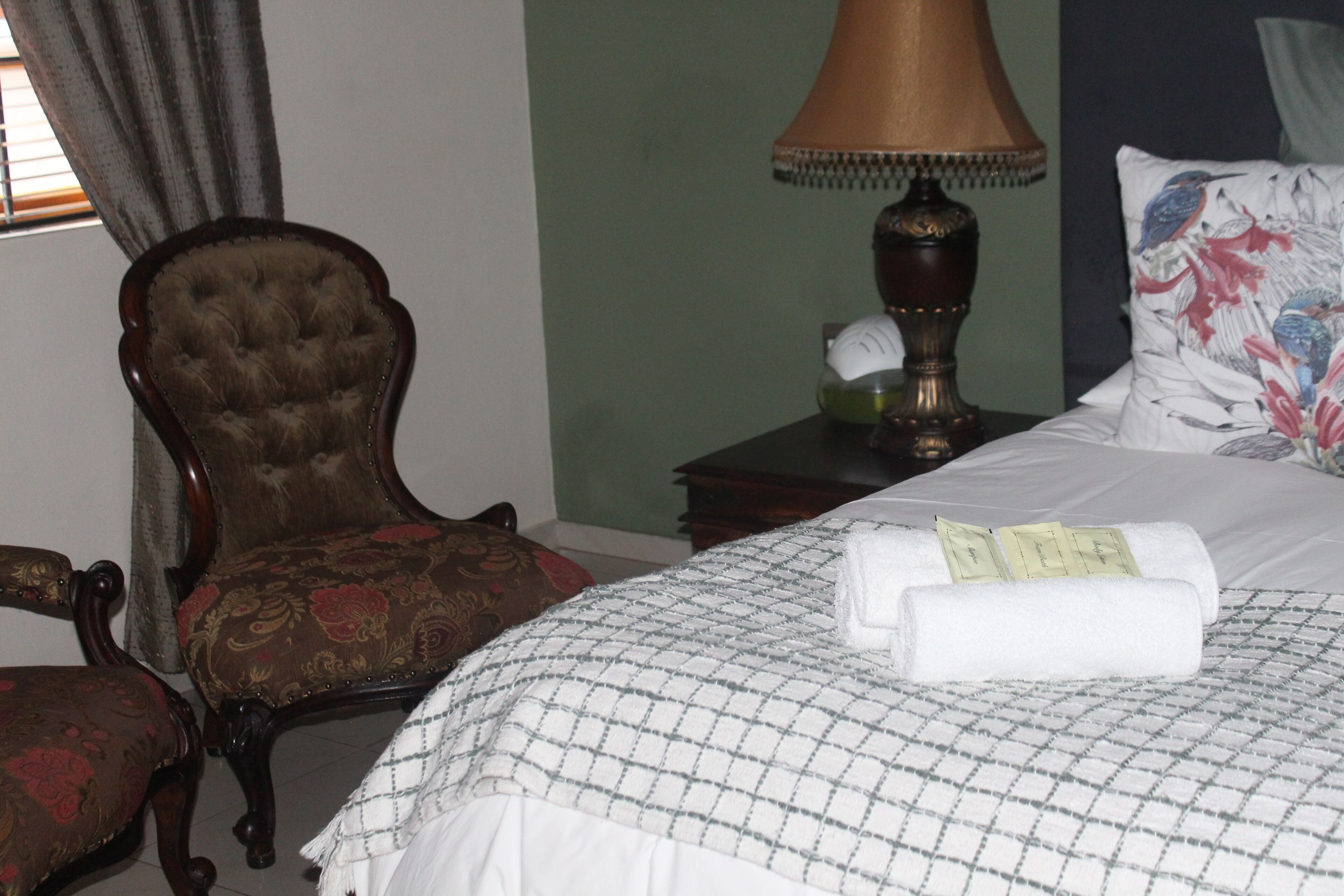 A hotel room with a bed, a chair, a lamp, and a nightstand.