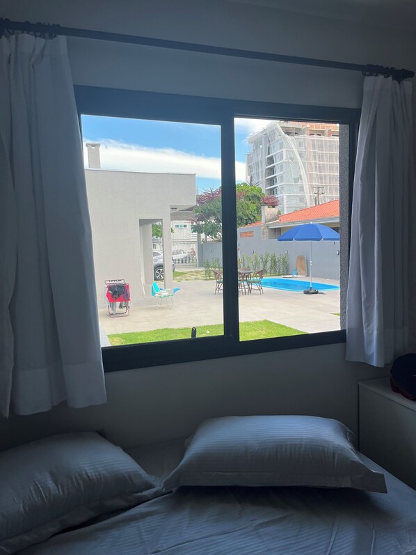 Enjoy a serene view of the outdoor area from the large window, featuring a comfortable bed and stylish curtains.