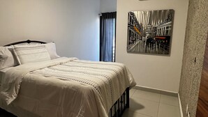 Ein Schlafzimmer mit einem Bett, einer Deckenleuchte, einer Klimaanlage und einem Wandbild.