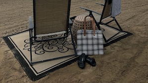 Ein Strand mit zwei Stühlen, einem kleinen Tisch, einer Tasche und einem Paar Schuhe im Sand.