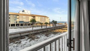 Un hôtel avec vue sur la plage, doté d’une promenade en bois, de palmiers et d’une plage de sable.