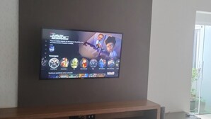 Een flatscreen televisie bevestigd aan een muur boven een houten dressoir.