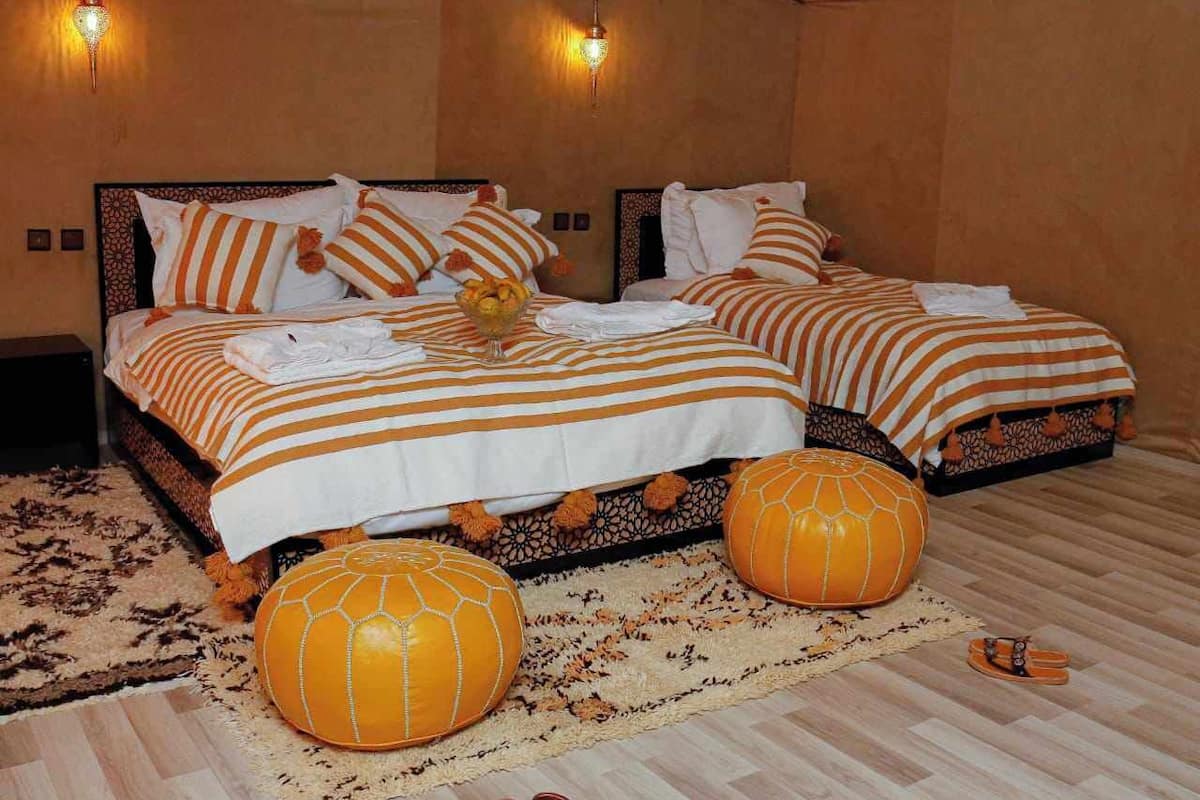 A bedroom with two beds, striped bedding, decorative pillows, and a large orange pumpkin ornament.