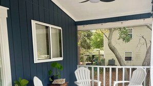 A covered porch with white Adirondack chairs, a ceiling fan, and a potted plant. - Wavy Navy - 2 Queen Beds - Centrally Located - Kill Devil Hills OBX (Kill Devil Hills)