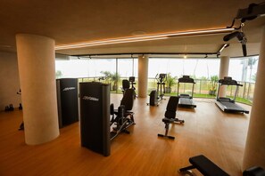 Ein Fitnessraum mit Cardiogeräten, Krafttrainingsgeräten und einer Bank.