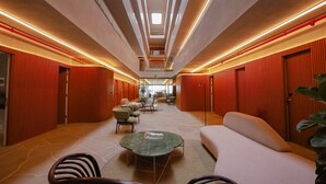 Un hall d'hôtel moderne avec un espace salon central, un escalier et une vue sur le hall en arrière-plan.