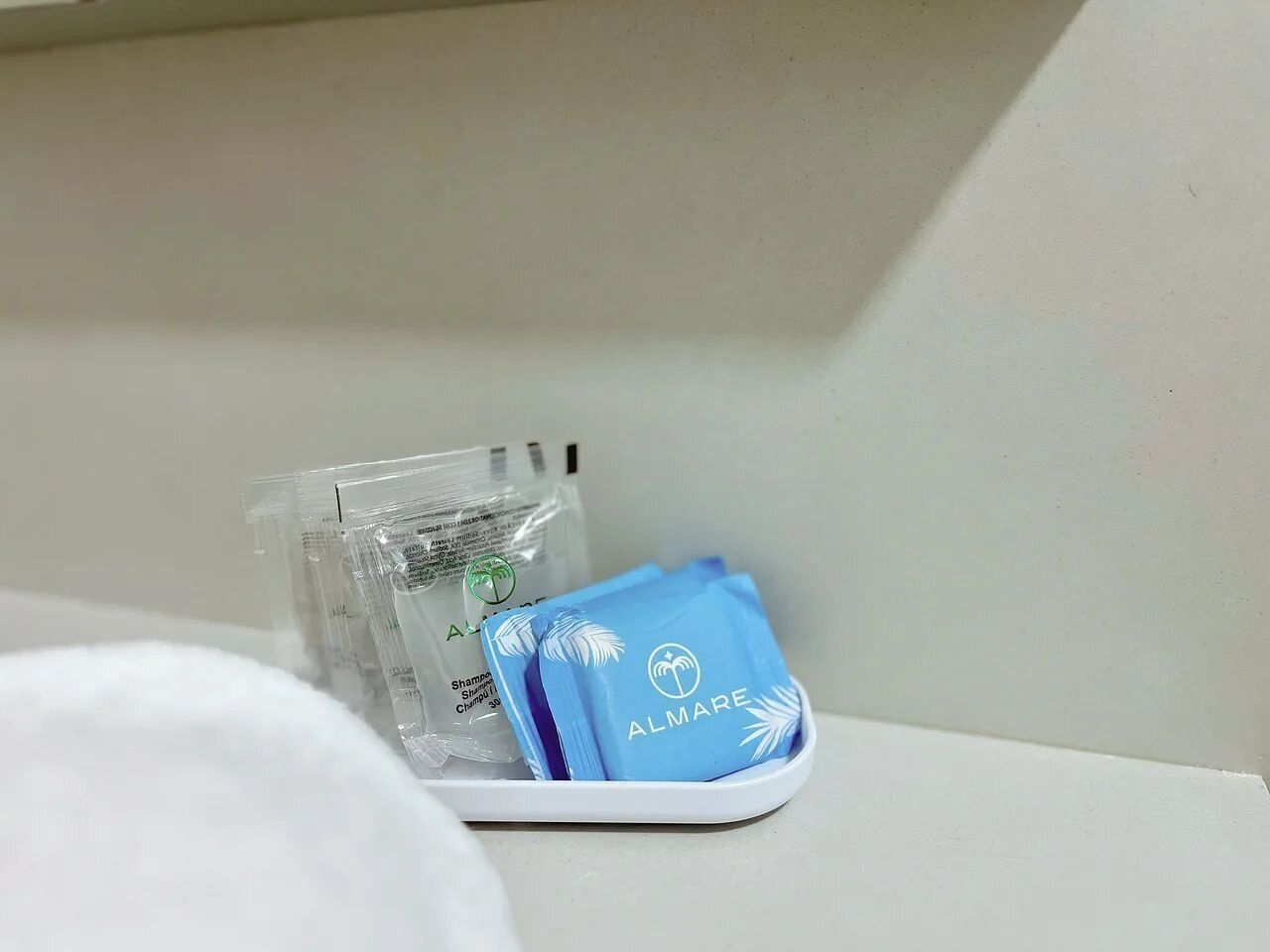 A white tray with a blue ALMARE bag and a clear plastic bag containing a product.