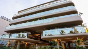 Un bâtiment moderne doté de nombreux balcons, de grandes fenêtres en verre et de plantes d’intérieur.