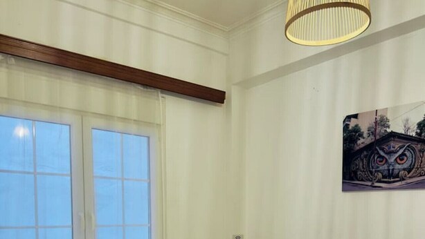 A neatly made bed with white linens and rolled towels, a bedside table with a lamp, and a window with curtains.