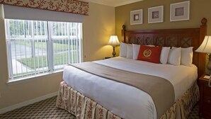 A hotel room with a large bed, two bedside lamps, a window with a view of the outside, and a decorative headboard. - Charming 2-bdrm villa in Lake Buena Vista, Florida near all family attractions. (Lake Buena Vista)