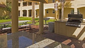An outdoor patio area with a grill, picnic tables, and a covered seating area. - Charming 2-bdrm villa in Lake Buena Vista, Florida near all family attractions. (Lake Buena Vista)