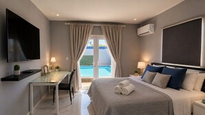 A modern hotel room with a bed, a desk, a TV, and a view of a pool. - Modern 3-bedroom villa with private pool, great alarm system, WiFi, hot water! (Noord)