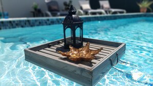 A wooden floating platform with a lantern and a shell decoration in a pool. - Modern 3-bedroom villa with private pool, great alarm system, WiFi, hot water! (Noord)