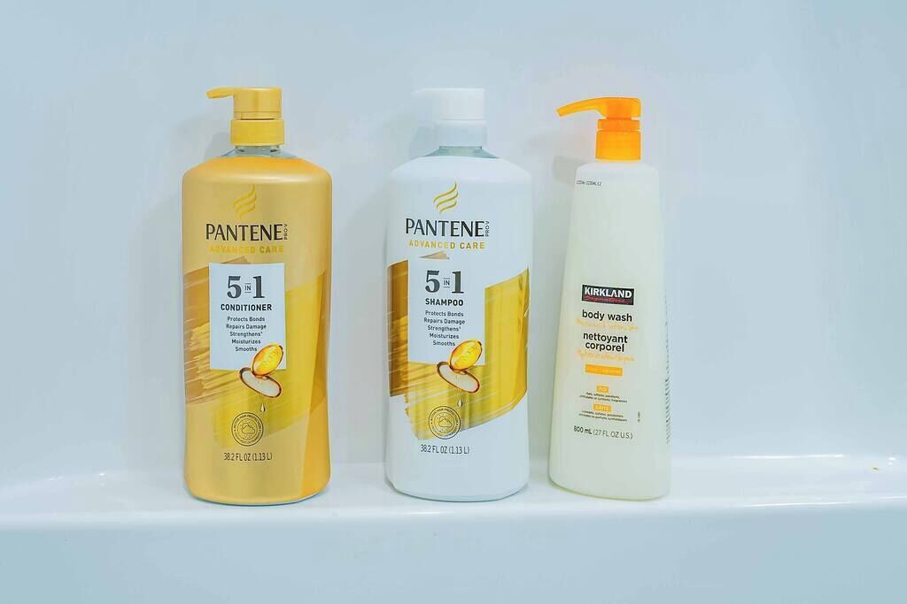 Trois produits de la marque Pantene pour les soins capillaires, présentés sur une étagère.