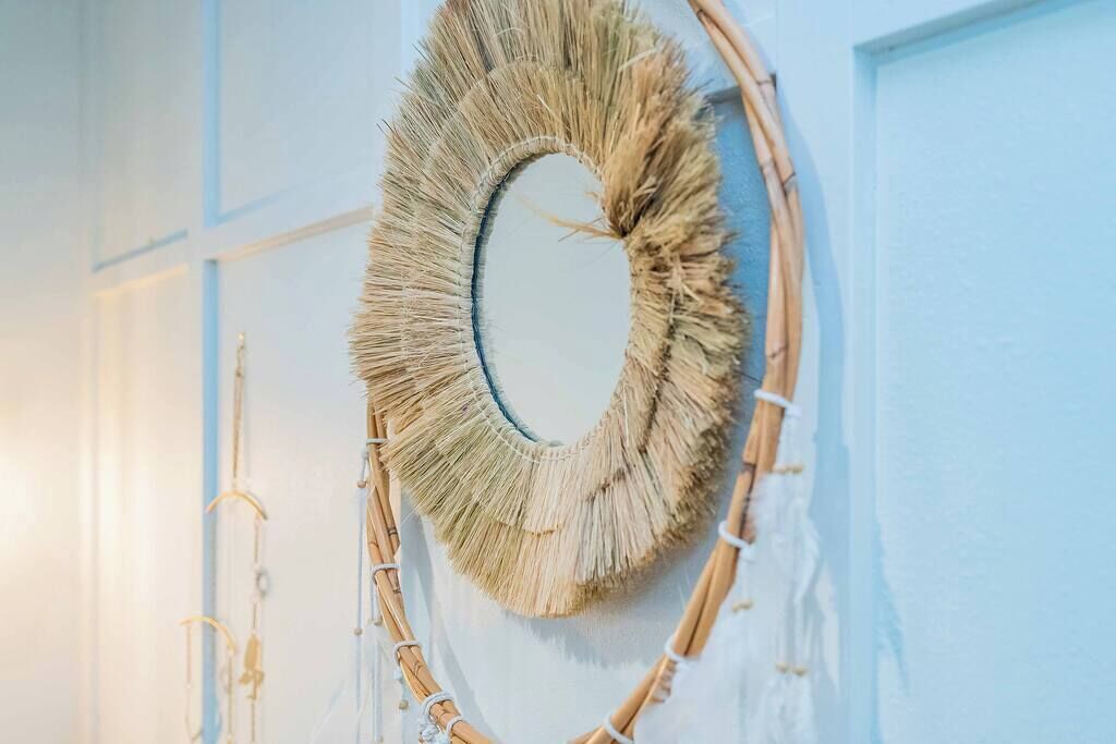 A circular woven wall decoration against a light blue wall.