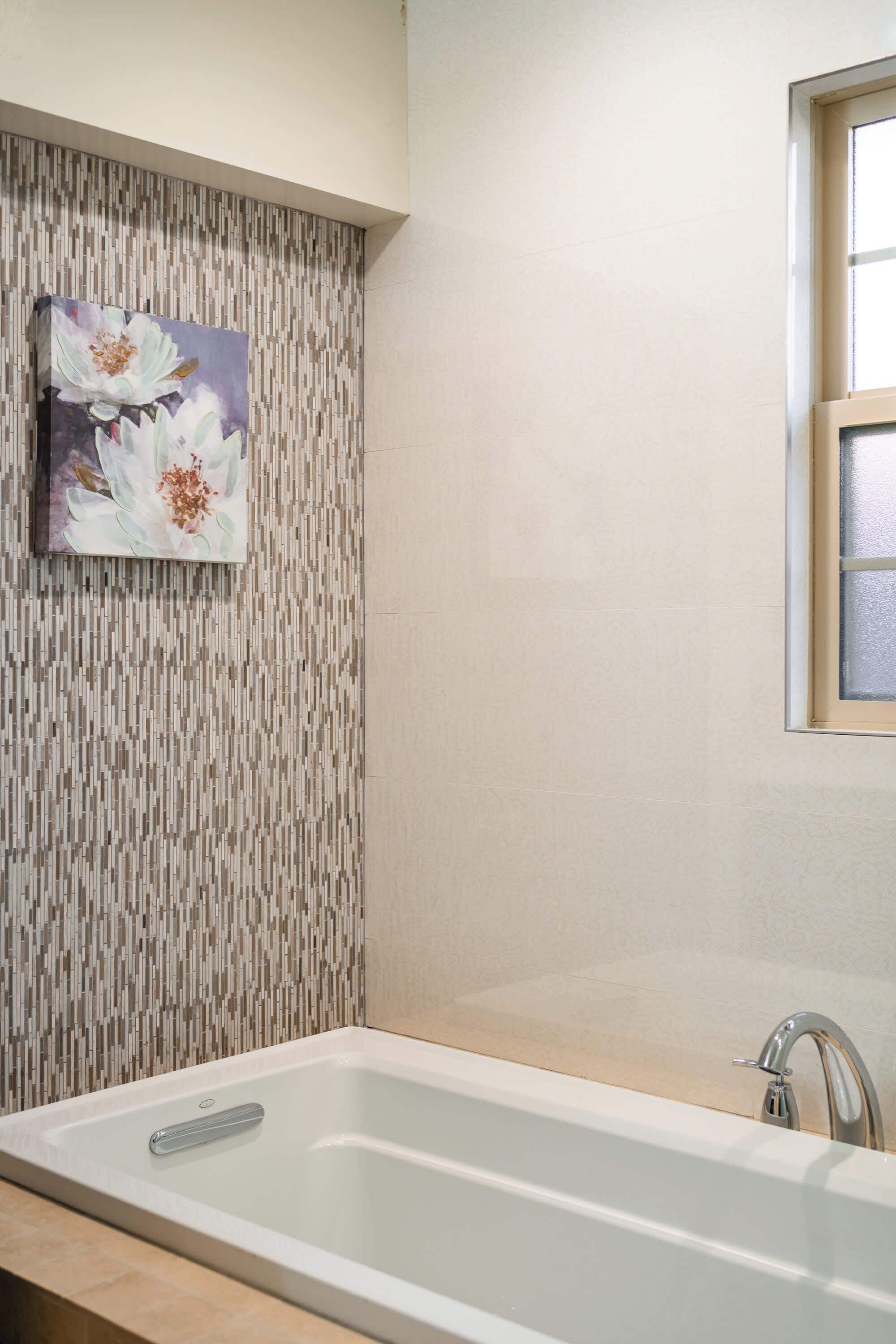 Un baño con una bañera rectangular, un lavabo instalado en la pared y una ventana.