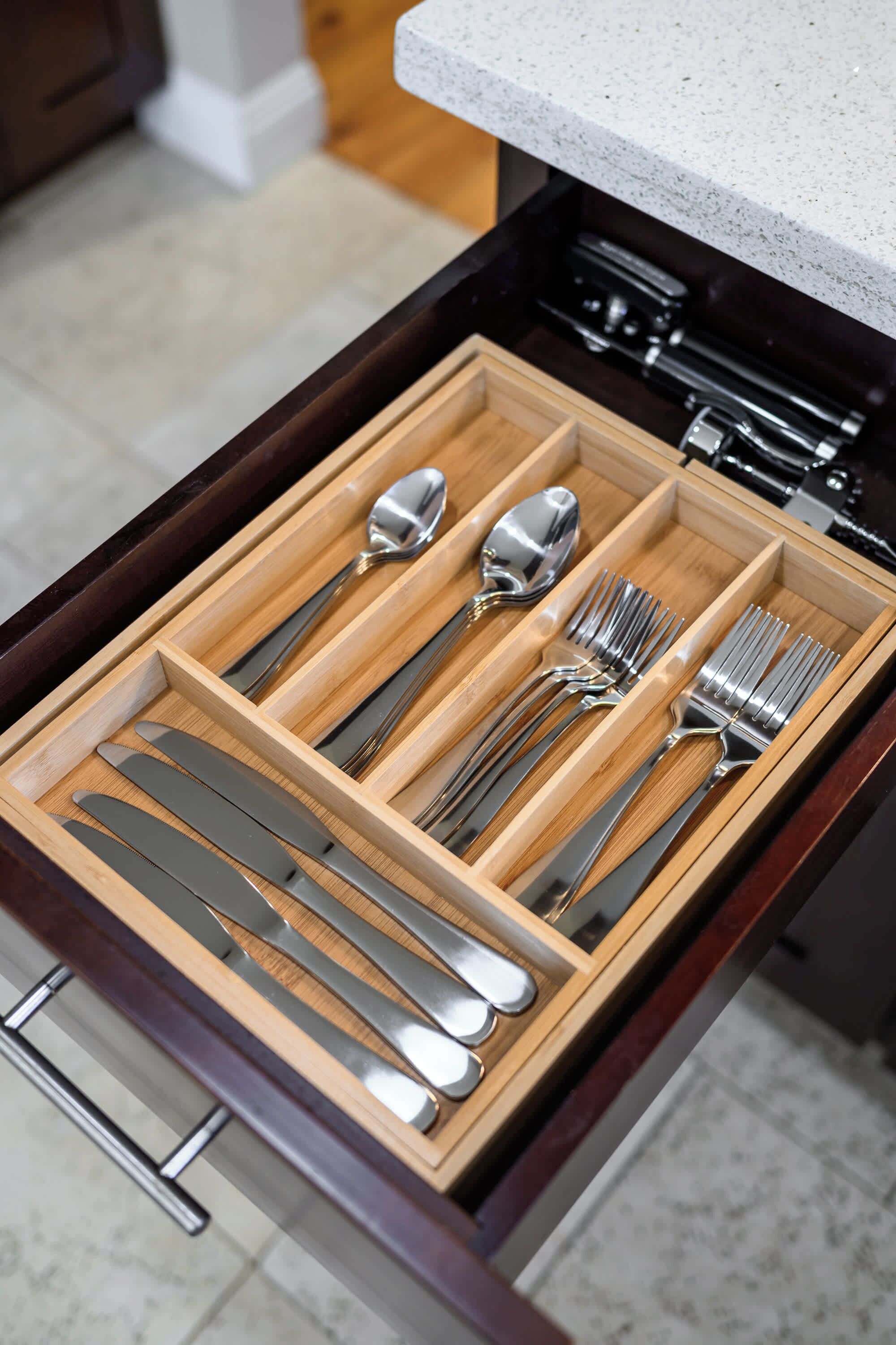 A drawer with neatly organized cutlery including knives, forks, and spoons.