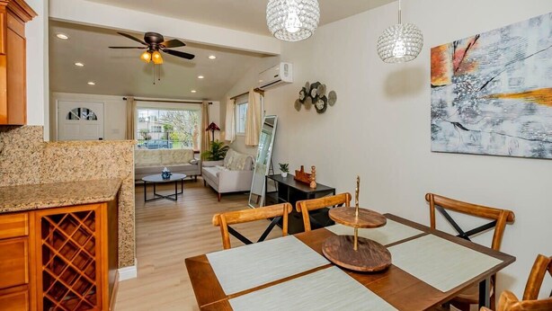 A modern kitchen with granite countertops, a dining area with wooden chairs and a round table, and a ceiling fan. - Modern Luxury in San Gabriel Valley Retreat (Glendora)