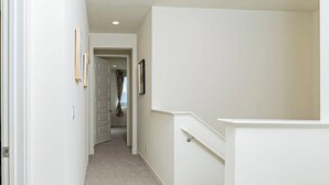 A hallway with white walls, a carpeted floor, and recessed ceiling lights. - Luxurious Ontario Townhouse: Ideal Family Retreat (Ontario)