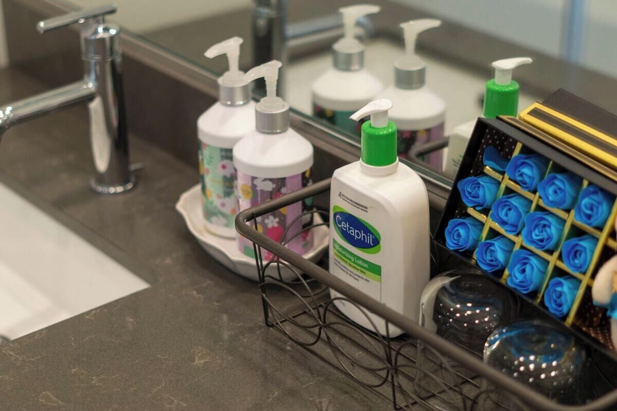A bathroom counter with a hand soap dispenser, a lotion bottle, and a tray of blue roses.