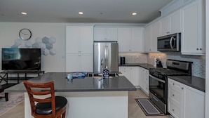 A modern kitchen with white cabinets, stainless steel appliances, and a central island. - Luxurious Ontario Townhouse: Ideal Family Retreat (Ontario)