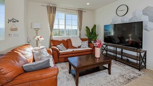 A living room with a leather sofa, a wooden coffee table, and a TV on a wooden stand. - Luxurious Ontario Townhouse: Ideal Family Retreat (Ontario)