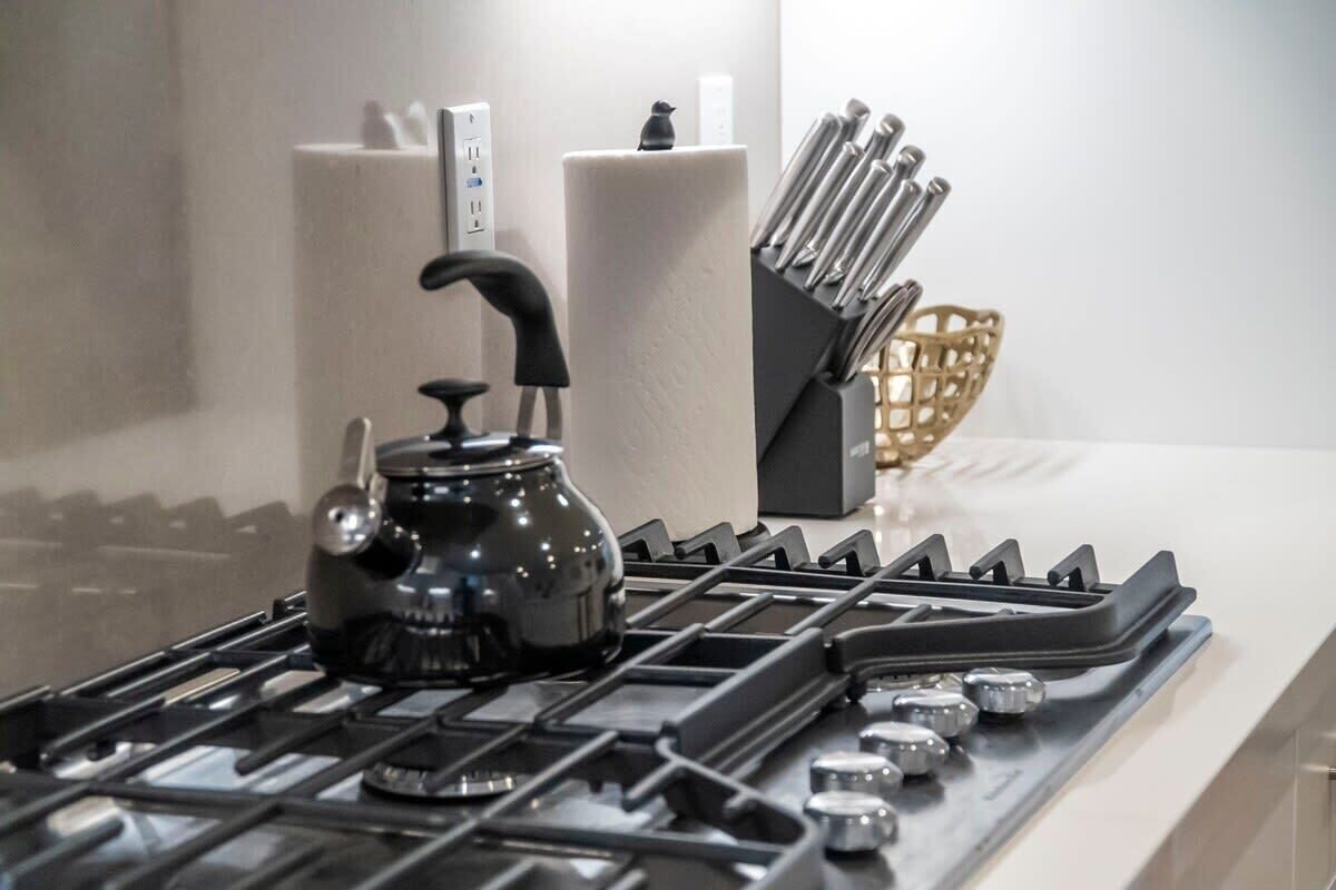 Une cuisine équipée d’une cuisinière à gaz, d’une bouilloire, d’un bloc à couteaux et d’un rouleau d’essuie-tout.