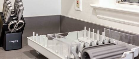 A kitchen area with a dish rack, a knife block, and a power outlet on the wall.