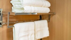 A wooden wall with a metal towel rack holding two neatly folded white towels. - Urban Glamping Oasis: Comfort & Adventure Combined (Glendora)