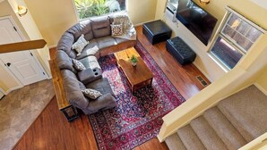 Un salon spacieux avec un grand canapé d’angle, un téléviseur à écran plat et une table basse en bois.