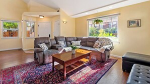 Un salon avec un canapé d’angle, une table basse et un tapis à motifs.