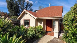 Une maison de plain-pied avec un toit recouvert de tuiles rouges, une porte d’entrée et un petit porche.