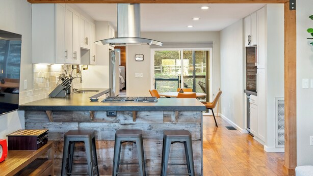 Una cocina moderna con una isla grande, taburetes de bar y suelo de madera.