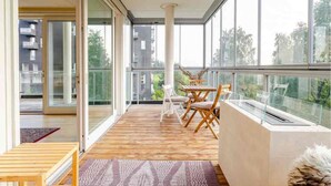 A balcony with a wooden floor, glass doors, and a table with chairs. - Spacious 3-bedroom with 3 balconies, 2 bthrms, sea view and free indoor parking (Oslo)