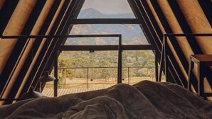 Un dormitorio abuhardillado triangular con cama y vistas a las montañas.