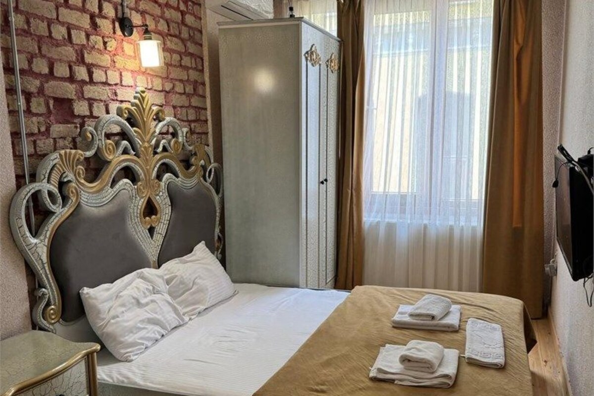 Een hotelkamer met een bed, een kledingkast, een nachtkastje en een televisie.